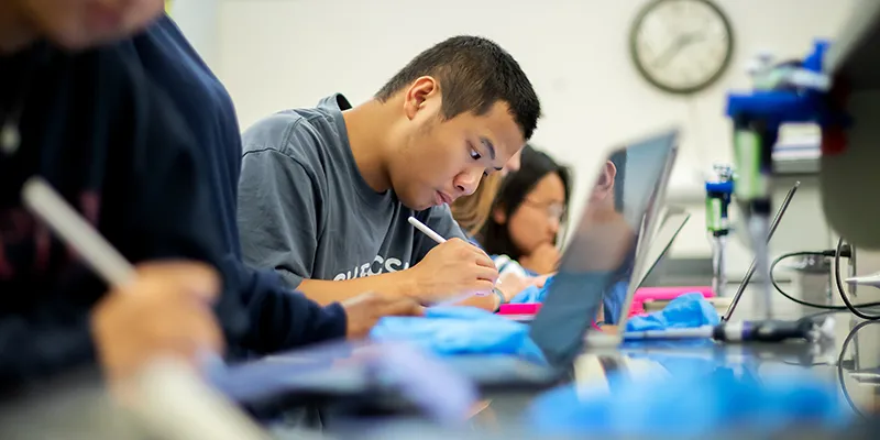 Penn students work intently in a lab classroom, using laptops and styluses, reflecting academic focus supported by The Penn Fund.
