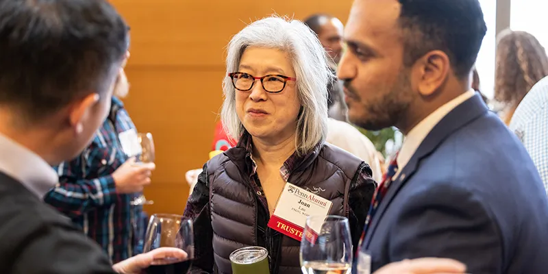 Alumni gather for a networking moment during a Penn reunion celebration indoors.