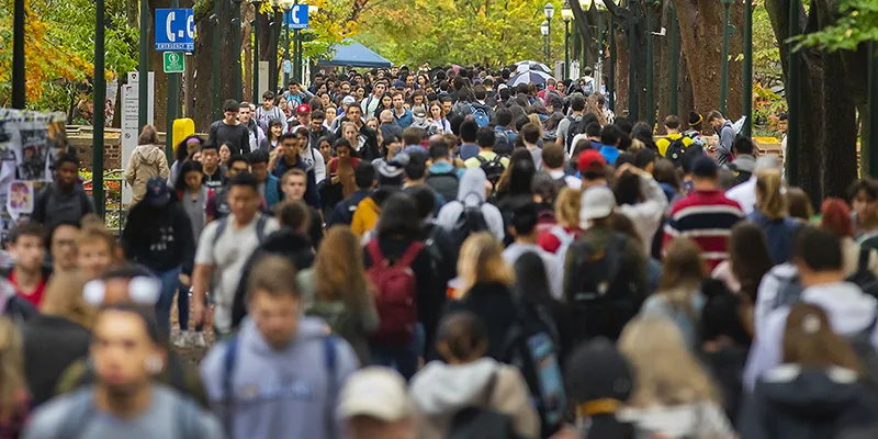 A crowd of students walks along Locust Walk in fall, representing the broad impact of matching gifts through The Penn Fund.