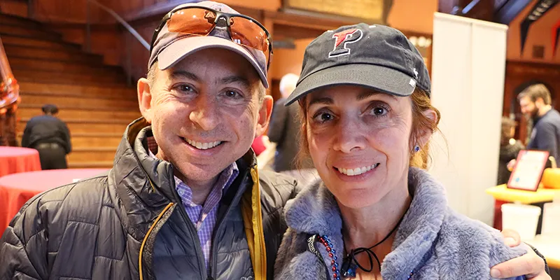 Two smiling Penn supporters wearing branded hats pose together at a campus event, reflecting the spirit of recurring giving to The Penn Fund.