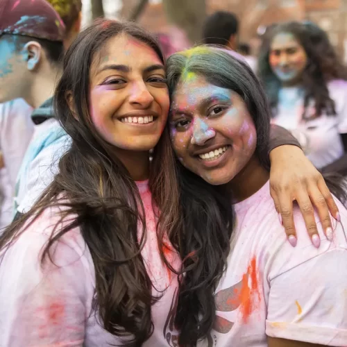 Friends embrace at a Holi festival event on Penn’s campus, highlighting the cultural celebrations and community made possible by donor support.