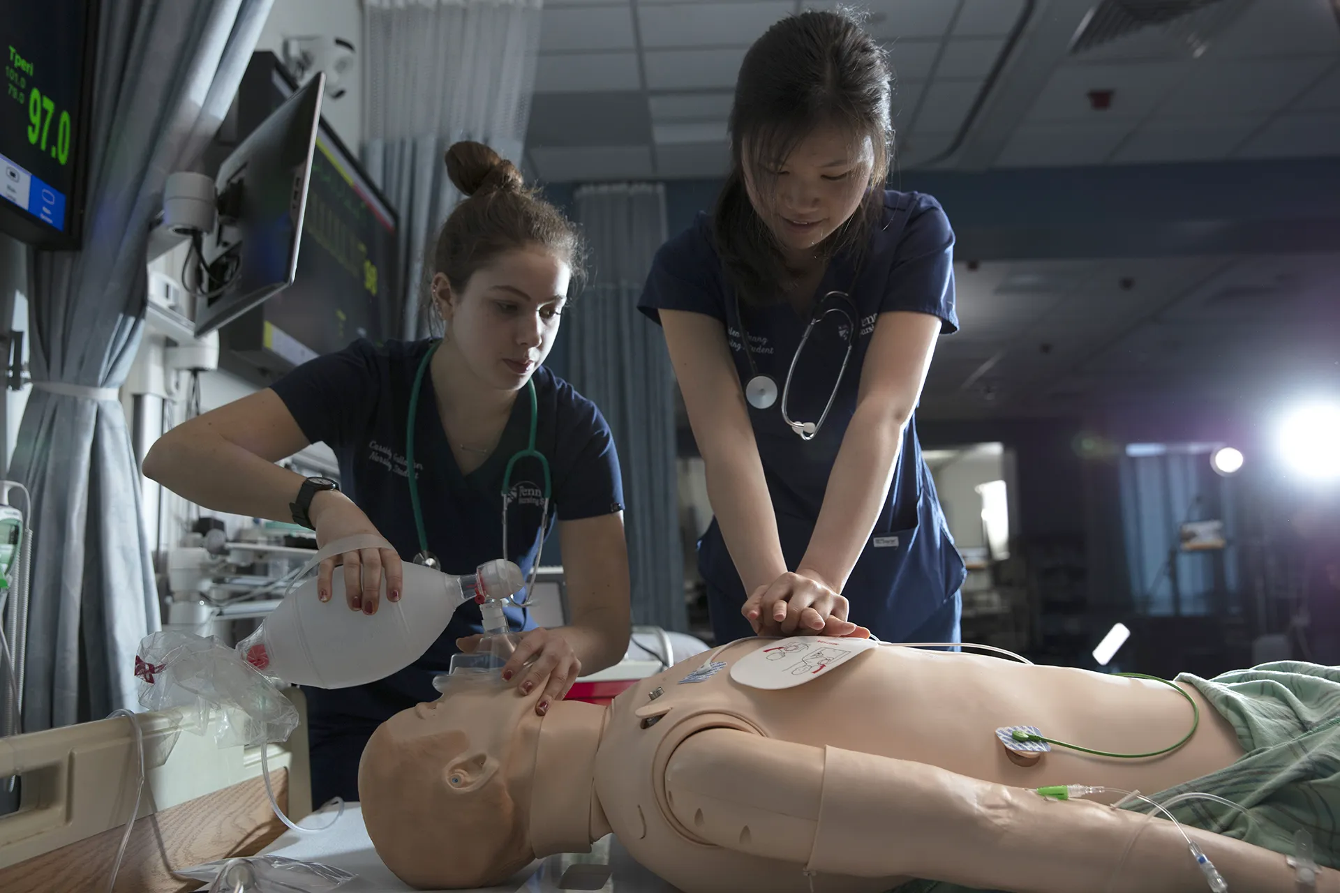Two nursing students perform CPR and bag-mask ventilation on a high-fidelity manikin during a training exercise in the Penn Nursing Simulation Center.