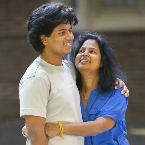 A smiling parent embraces their Penn student on campus, symbolizing the support and impact of families who give to enhance the student experience.