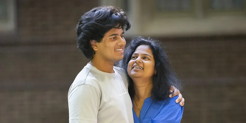 A smiling parent embraces their Penn student on campus, symbolizing the support and impact of families who give to enhance the student experience.