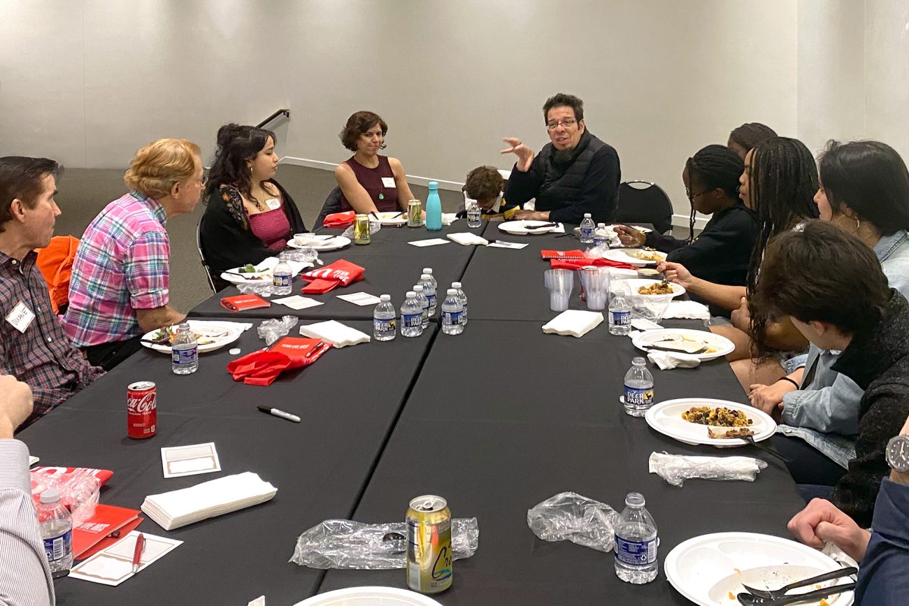Jairo Moreno gestures with his hand while speaking to a diverse group of individuals seated at a table