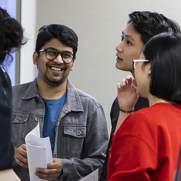 A group of students from Penn's School of Social Policy and Practice engaged in conversation, holding papers and smiling.