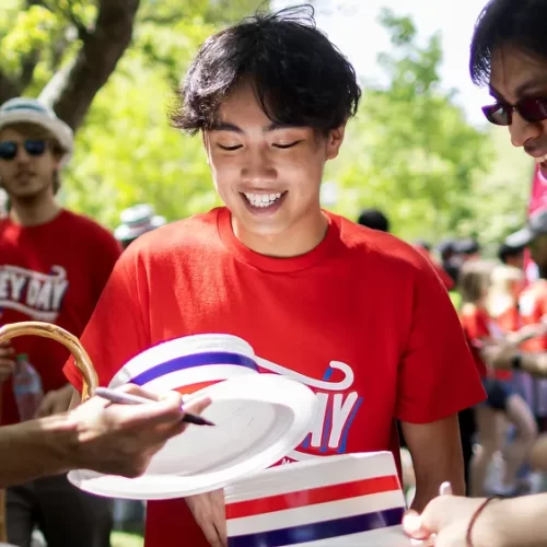 A group of University of Pennsylvania students celebrates Hey Day in matching red shirts and white hats.