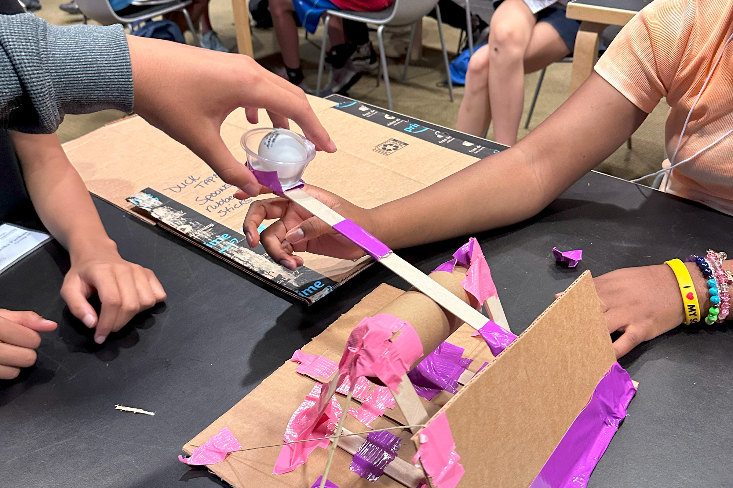 Campers work together to test their miniature catapult