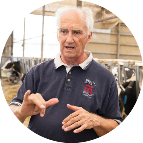Tom Parsons speaks and gestures with his hands while standing inside a barn.