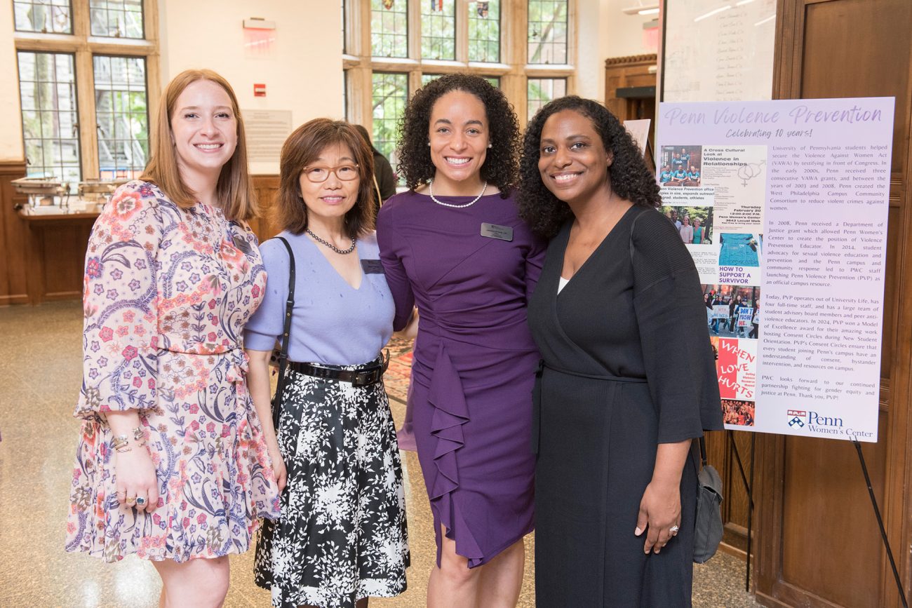 Four women smiling at an event, each dressed in professional attire.