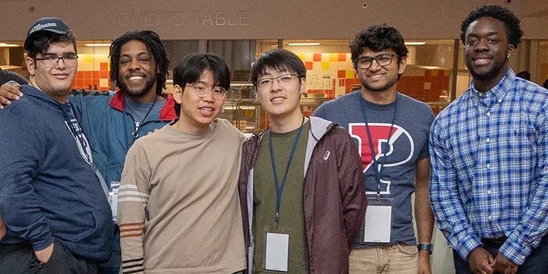 Group of young alumni smiling and enjoying each other's company.